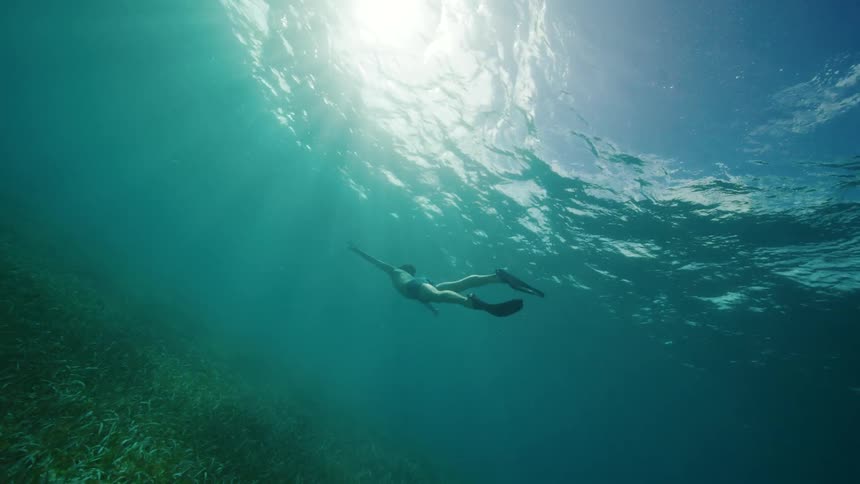 A male is swimming under the ocean water