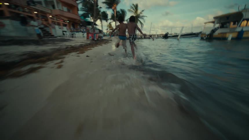 A group of kids are running by the beach and ocean
