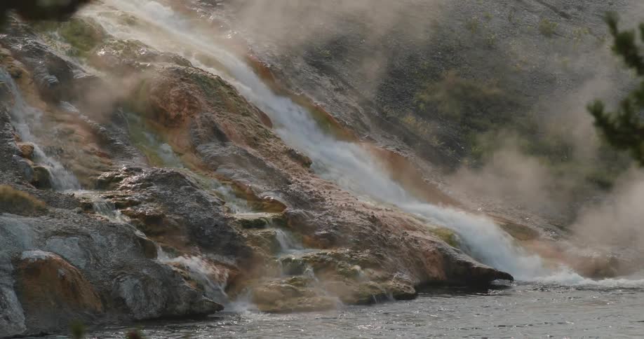 A waterfall is flowing down a mountain into a river