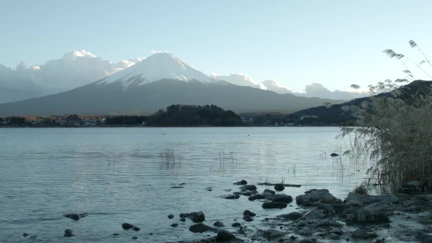 A lake is surrounded by rocks with a snow covered mountain in the distance