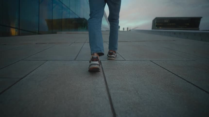 A person walks along a walkway on the outside of a building in the evening
