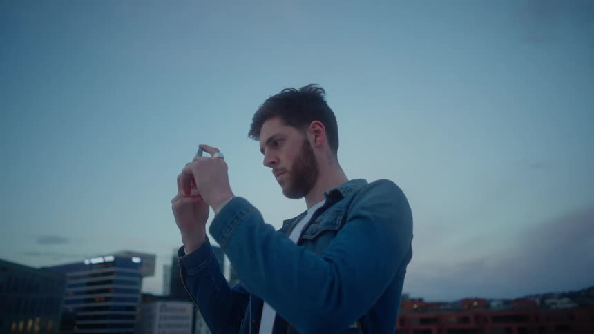 A man taking a picture with his smartphone near buildings in a city