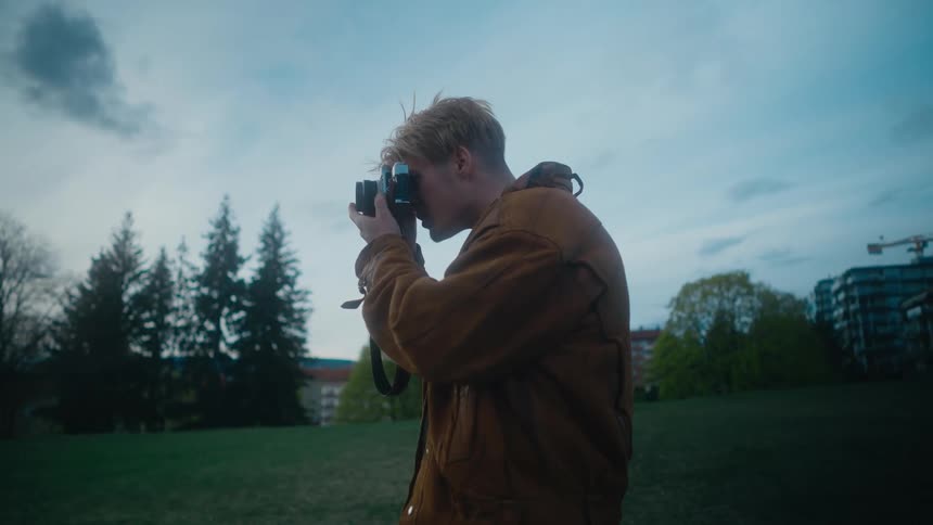 A teenage boy takes photos in a park