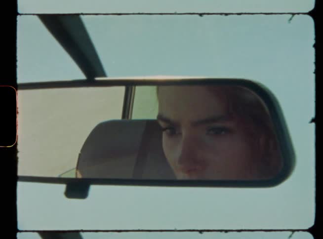 A woman is driving a car during sunset