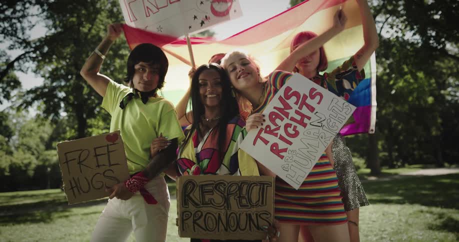 A group of kids hold signs and a rainbow flag