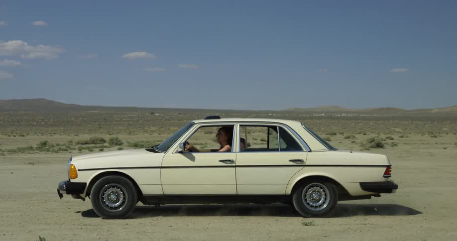A woman is driving a car through the desert