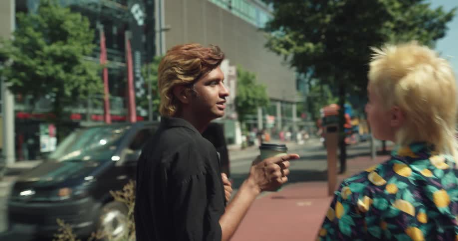 Man and woman are walking through a city and holding cups of coffee