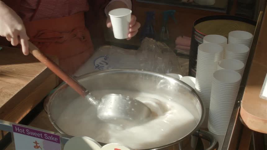 A person mixes something then spoons it into a cup