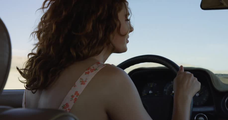 A woman is driving a vehicle through a rural area