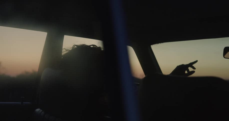 A woman is sitting in a car during sunset