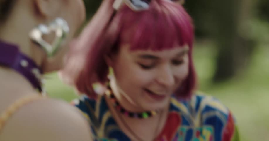 Woman with colorful short hair painting on the body of a friend in a park