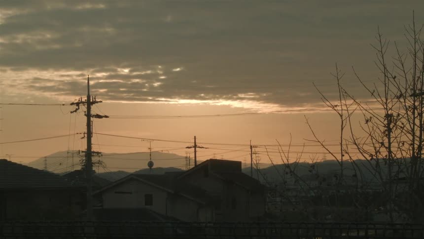 Sun setting on a mountain town on a cloudy evening