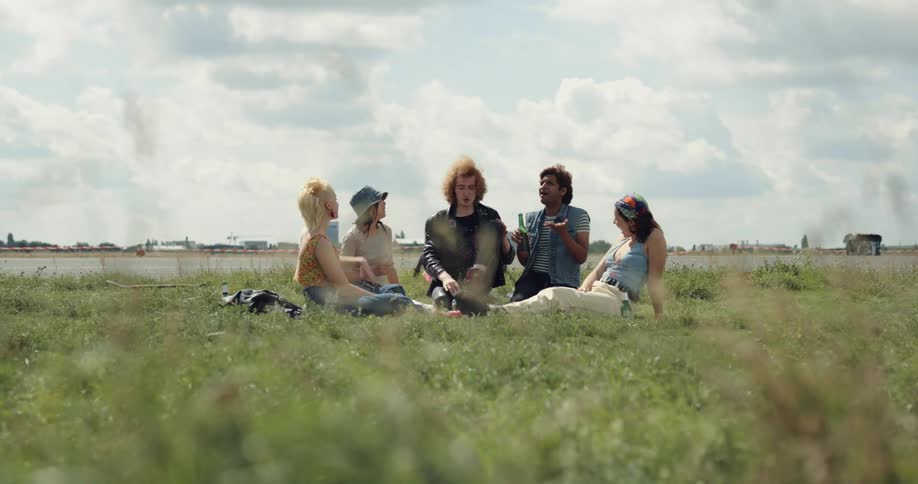 A group of friends are hanging outside in the grass