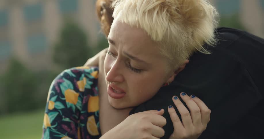 A man is hugging his friend that is crying and upset