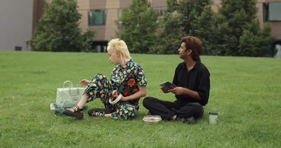 Two friends are sitting on the grass and hanging out