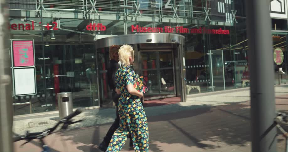 A young woman and man chat while walking together through a metropolis during the day
