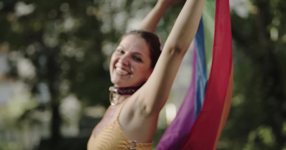 Woman smiles while spinning around with pride flag