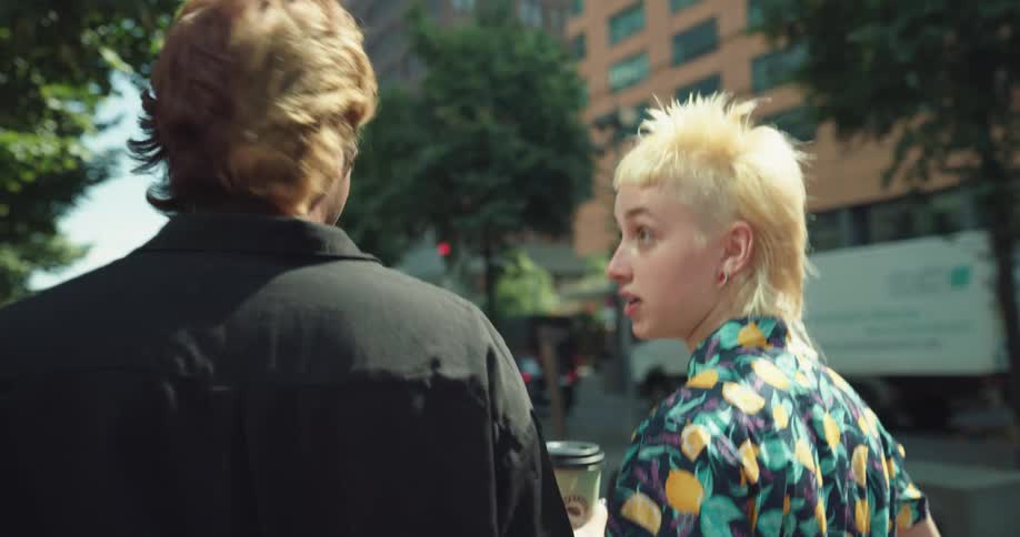 A man and woman walk together on a street side having a conversation