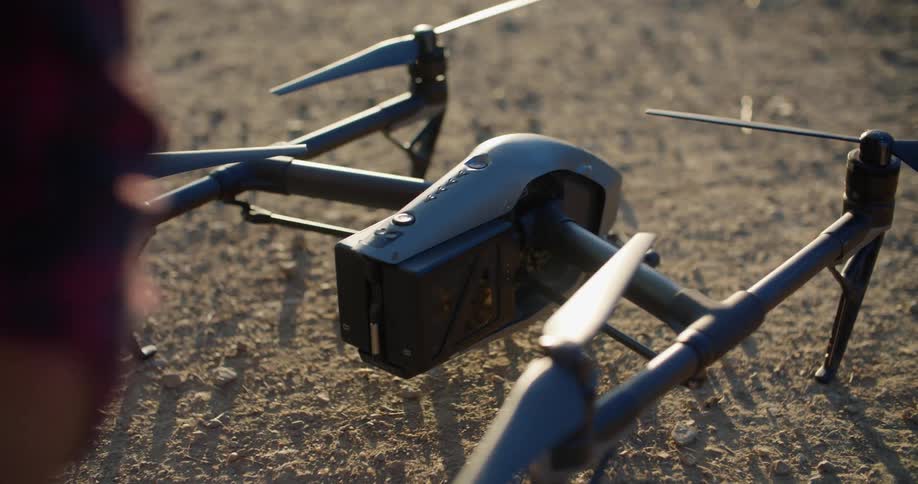 A man puts a battery in a drone sitting on the ground and turns it on