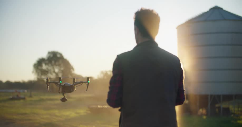 A man remotely controls an aerial drone as it rises into the sky