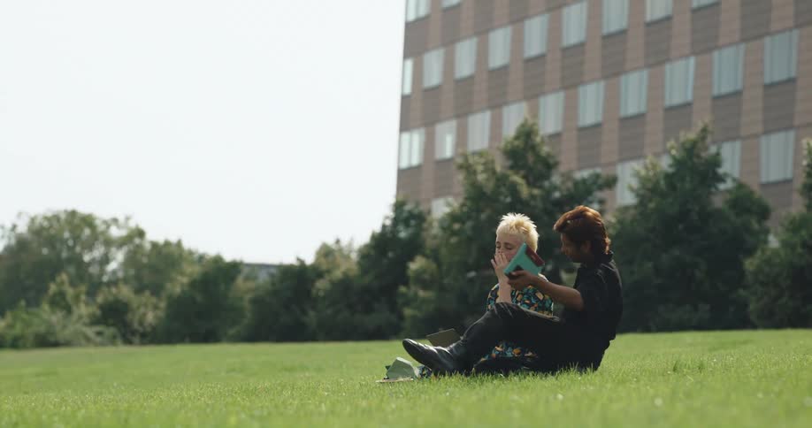 A man and woman sitting together on a grassy lawn outside
