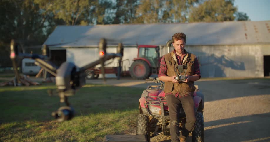 A man is standing outside operating a drone that is hoovering a few feet off the ground