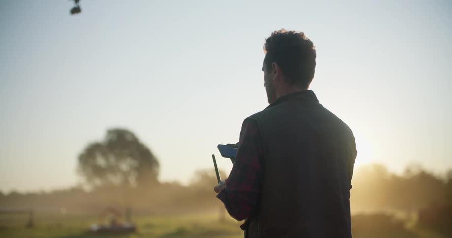 A man flying a drone in a rural field