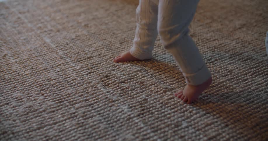A young baby learning to walk on a rug