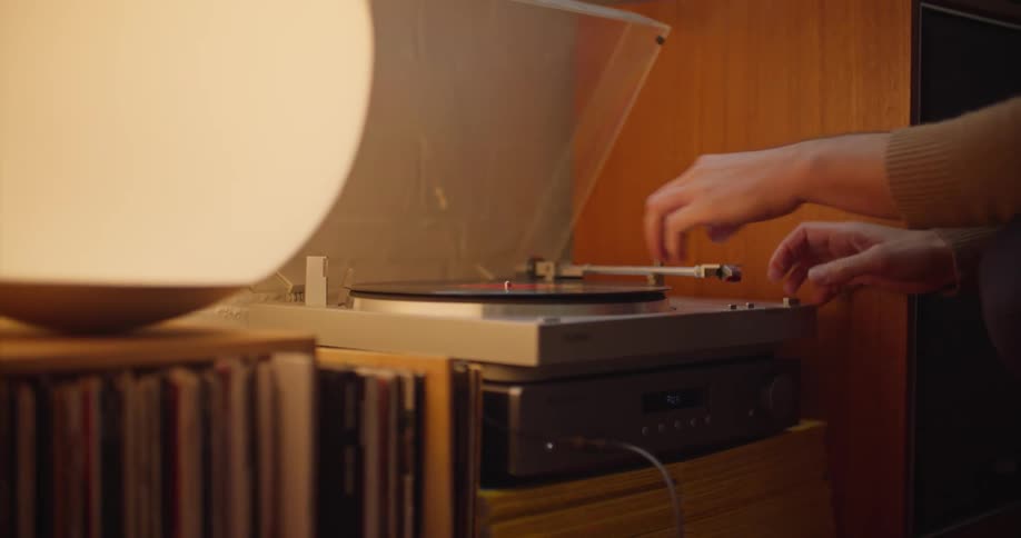A woman at home puts a record on a record player