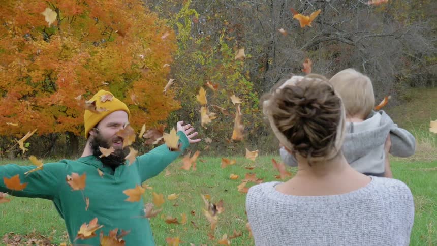 Two parents playing with their child in a pile of leaves