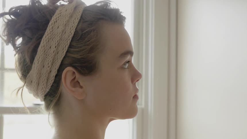 A woman puts something on the wall in front of her