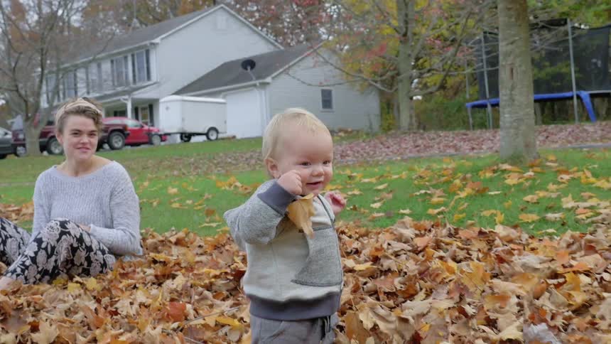 A baby and parents play in the leaves