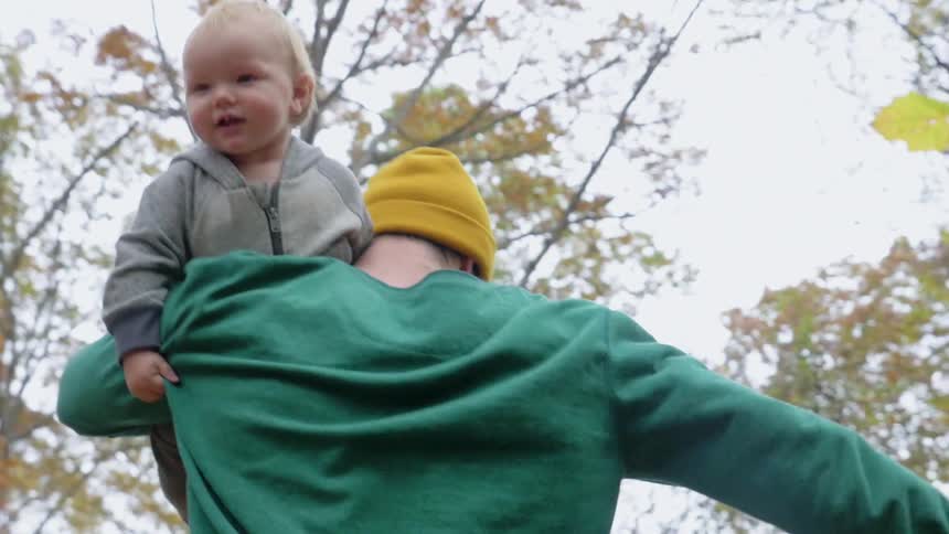 A man running through trees with a toddler on his shoulder