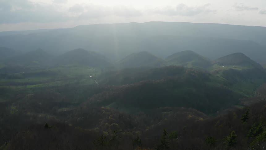 A man walks along the top of a hill overseeing rolling hills