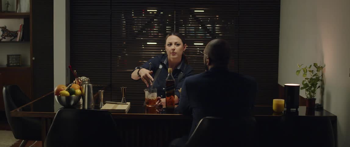 A bartender talks to a customer while preparing a drink at a small bar