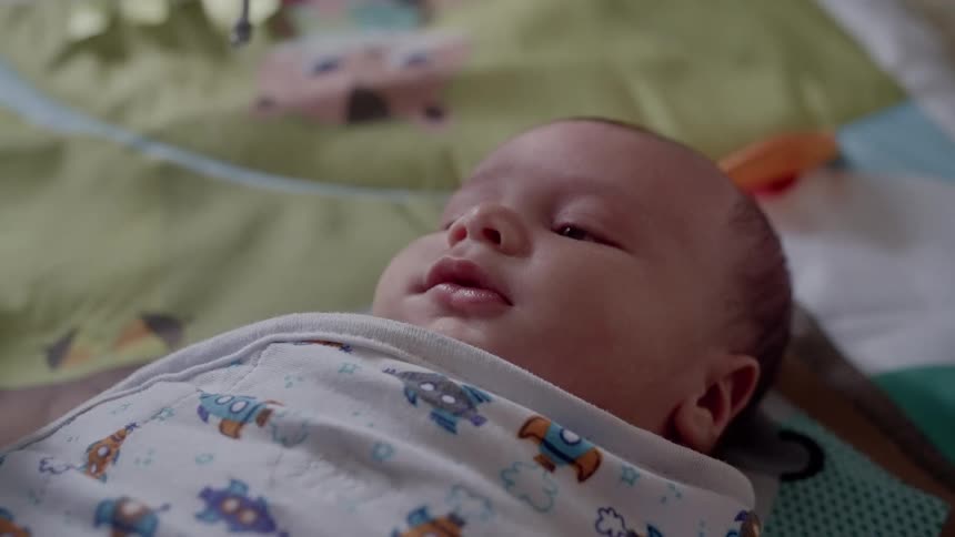 A swaddled newborn baby lying on a blanket