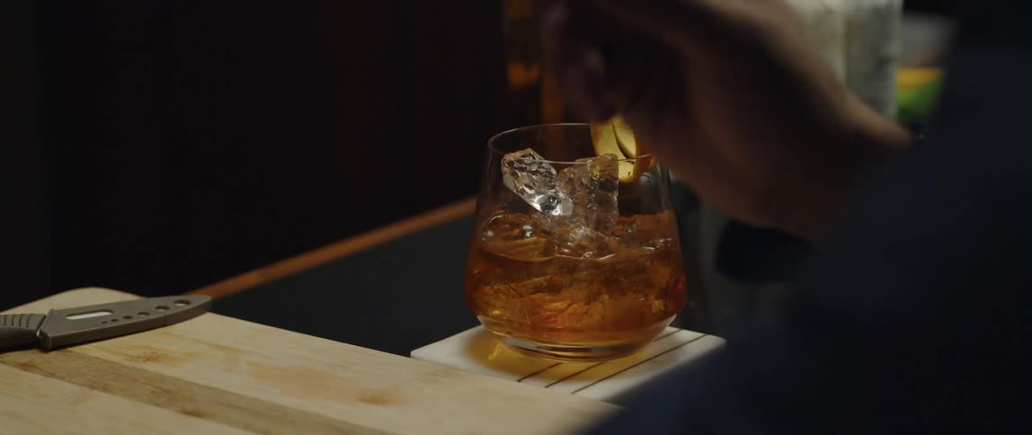 A man is sitting at the bar counter and getting drinks served to him