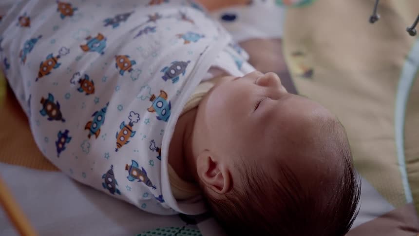 Mirror reflects light onto sleeping baby bundled in a blanket