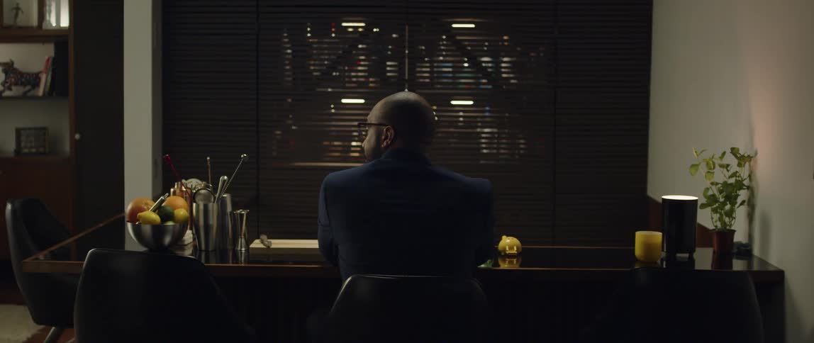 Bald man with beard and naval blue shirt sits at dining table