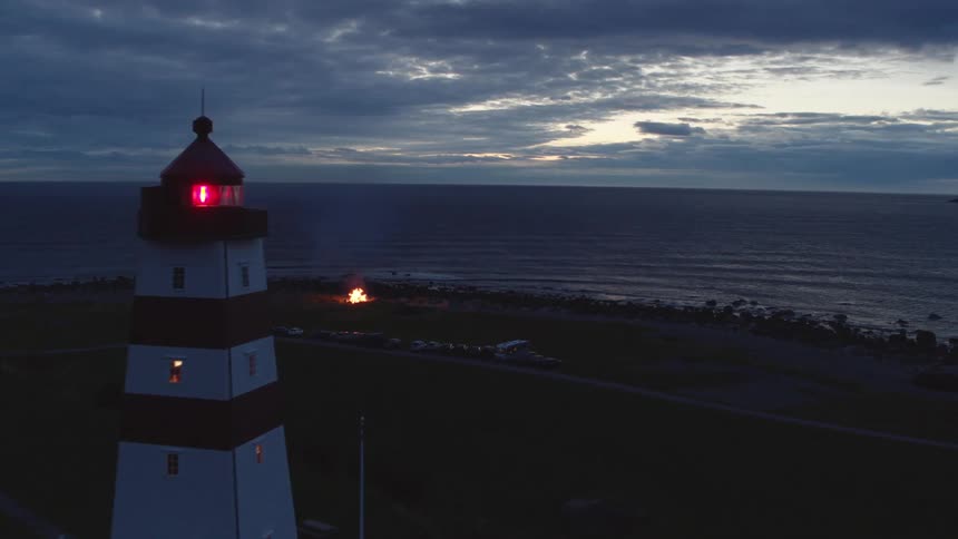 Aerial view of lighthouse near the sea and bonfire