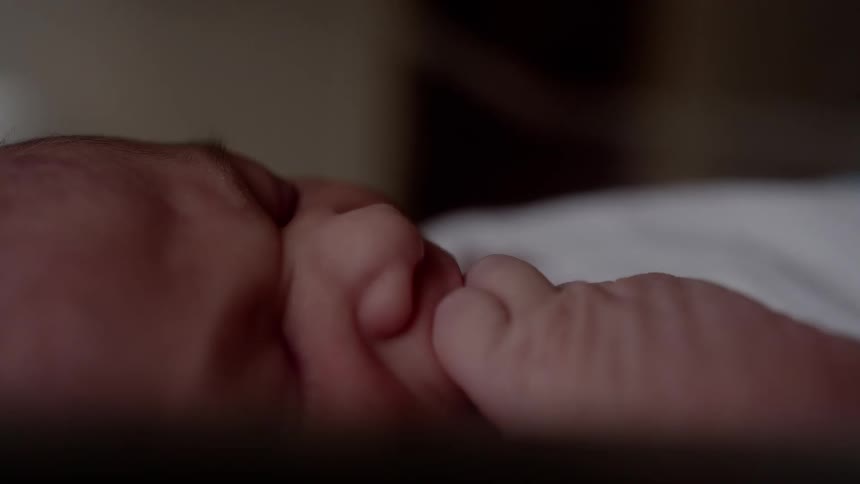 A baby chews on its fingers