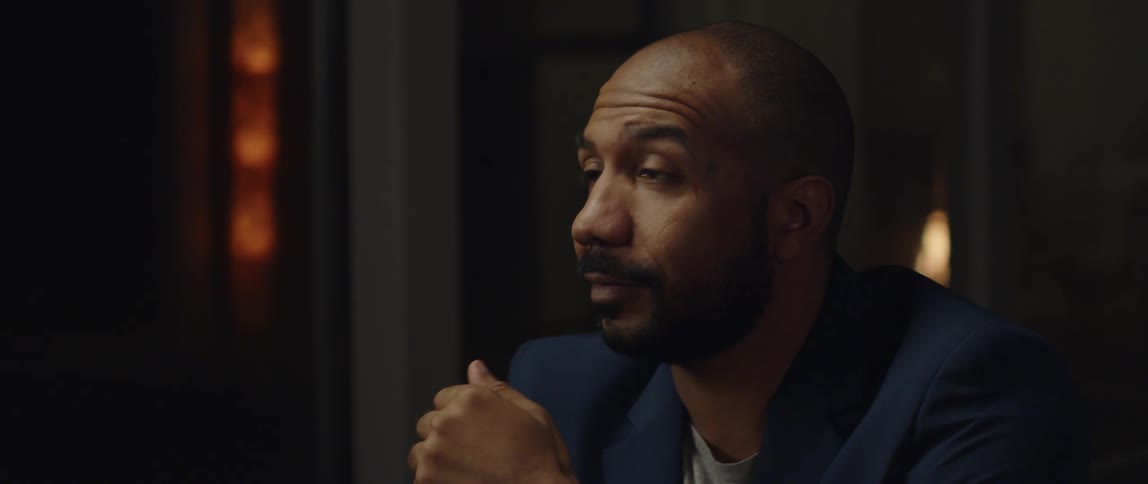 A black man is smiling and pointing with his finger