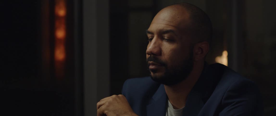 A man is sitting in a room and wearing a suit