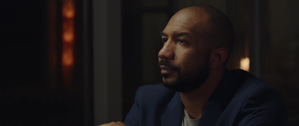 A man is wearing a suit and sitting in an empty room