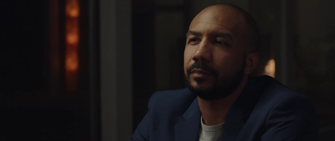 A man is sitting in a room and wearing a suit