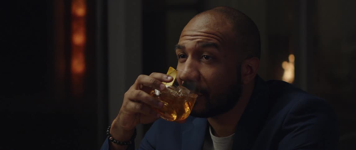 A man is sitting in a room and drinking a beverage