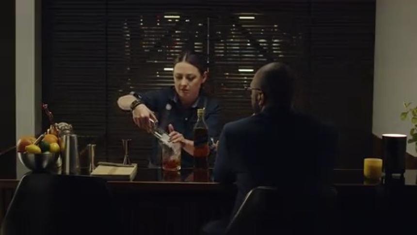 A female barkeeper is preparing a drink for a patron