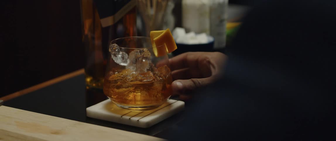 A black man is picking up his glass and drinking the alcoholic beverage