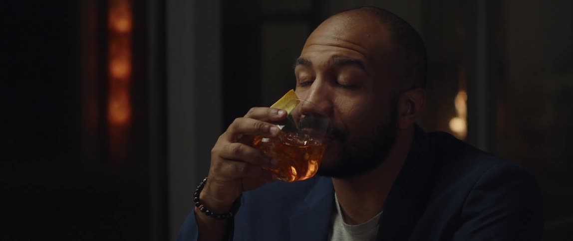 A man is drinking an alcoholic beverage indoors