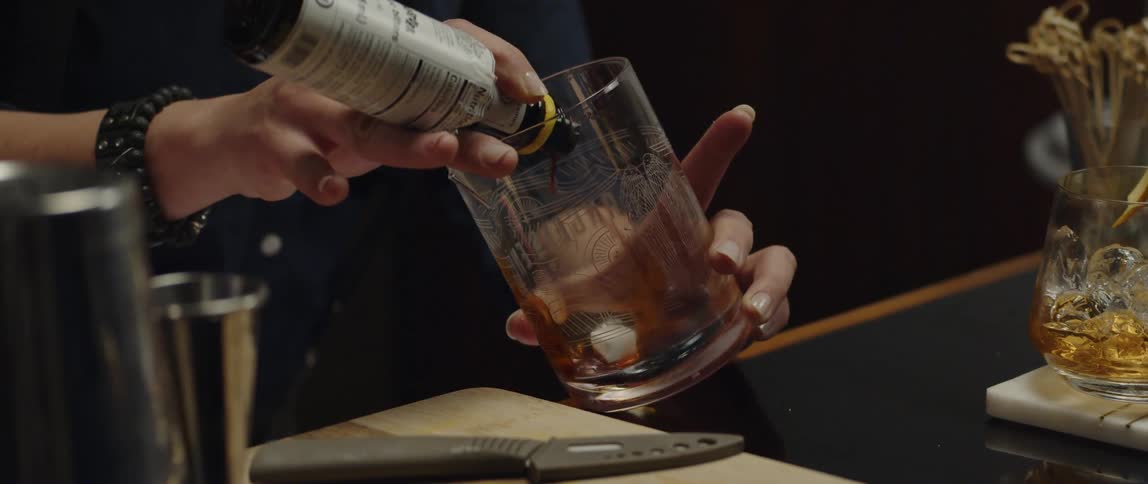 A woman is preparing a drink in a glass
